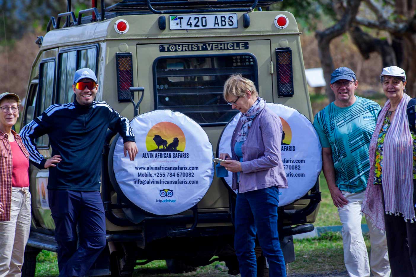 Tourists near safari vehicle.